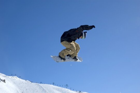a snowboarder jumping high through a blue sky