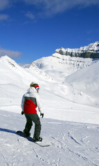 Girl snowboarding on the backdrop of scenic view in Canadian Rocky mountains ski resort