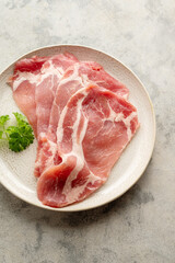 Raw bacon slices in a plate, top view. 
