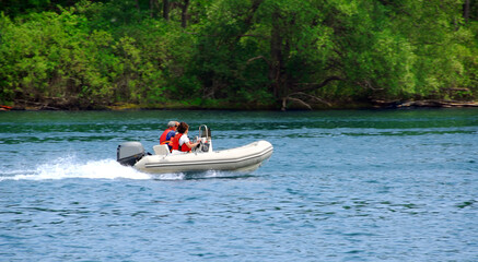 Fototapeta premium A couple driving an inflatable boat on a river