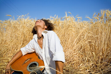 Naklejka na ściany i meble cool guy laying in a cornfield playing guitar