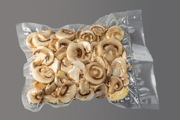 Cultivated white champignon mushrooms, sliced button mushrooms (Agaricus bisporus) in vacuum-packed for sous vide cooking on gray background