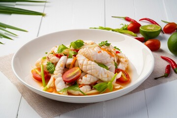 Thai Spicy Squid Salad,mixed squid with onion and tomato in chilli lime sauce in white plate.Thai food
