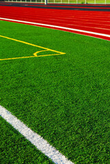 Red racetrack and green sports field with artificial grass