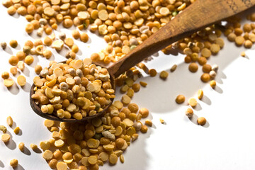 yellow peas (cereals) in the wooden spoon over white