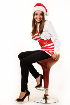 Attractive young brunette business woman sitting on bar stool wearing festive attire with santa hat