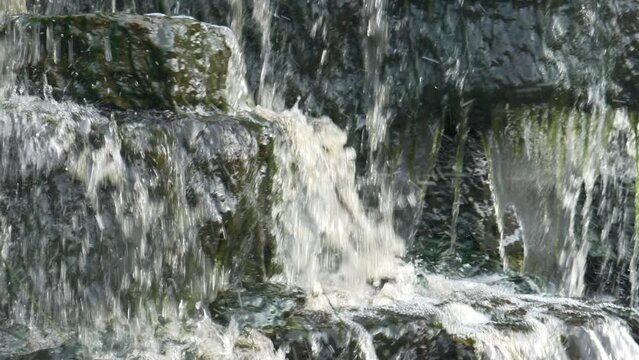 Waterfall, water flowing from the river falls down. A stormy river with a brown hue.