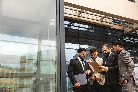 An international team of successful young business men in suits at a meeting are discussing the implementation of business plans together. Effective management and professional organization
