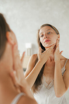 Woman applying cream on neck at home