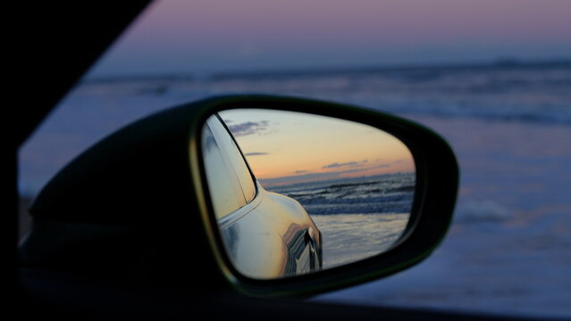 Sport car  back in mirror. Pink sunset on background.