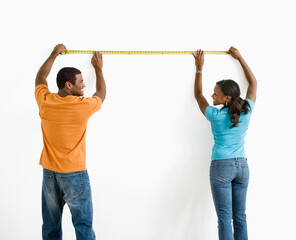 African American male and female measuring wall.