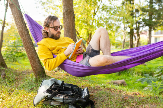 man writing in a notebook in a hammock