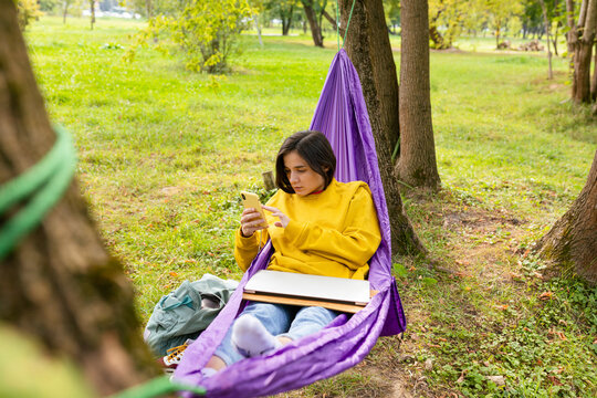 girl lies in a hammock and looks at the phone