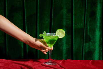 Unidentified barman holding martini glass with green cocktail