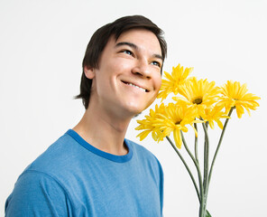 Asian young man holding bouquet of yellow gerber daisies smiling.