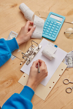 Hands of woman with receipt calculating expenses.
