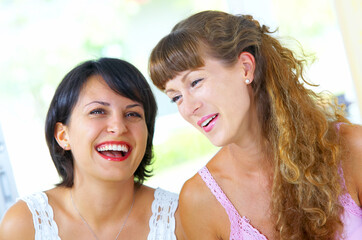 High key portrait of two young females laughing on something