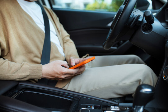 man or driver driving car and using smartphone