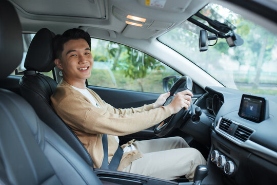 cheerful asian man inside his new car