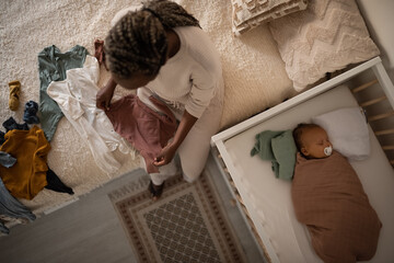 Black mother doing housework while baby sleeping