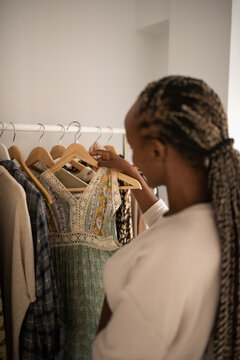 Black woman taking ornamental dress from rack