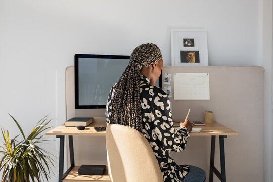 Black freelancer writing information in notepad