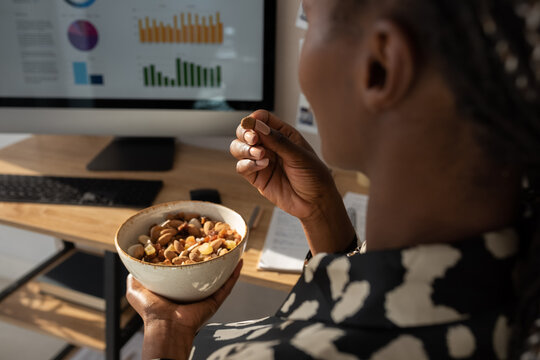 Black economist eating snacks during online work