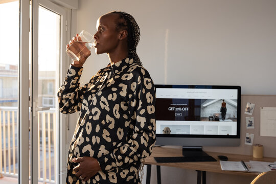 Black pregnant woman drinking water