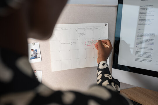 Crop businesswoman circling notes in schedule