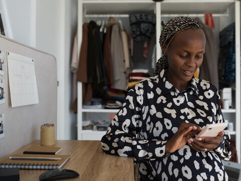 Black pregnant woman browsing mobile at desk