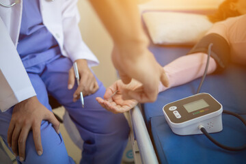 The doctor is using a blood pressure monitor on an elderly patient to check whether the blood pressure is abnormally high or not because hypertension often happens to the elderly and is dangerous.