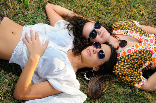 Portrait of two young girl friends lying on green grass field