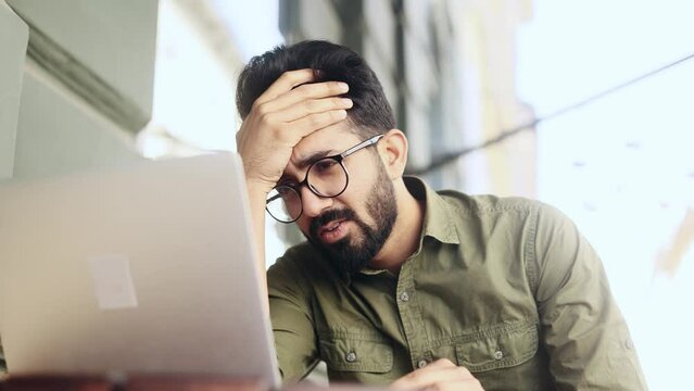 Worried young indian businessman freelancer waiting for important message with crossed fingers and reading bad negative news feeling disappointed upset at city cafe Defeat Loss Disappointment concept 