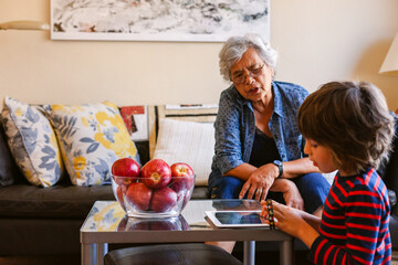 Grandmother looking at her grandchild using his tablet