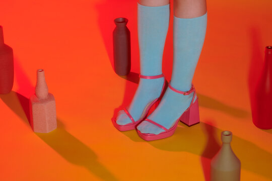 Women's legs in socks and a shoes on color paper background