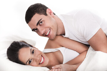 Young couple having fun in bed over white background
