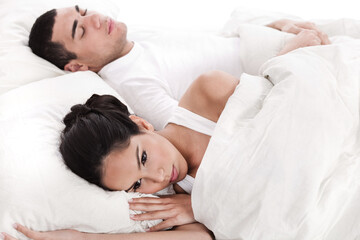 Fototapeta na wymiar Couple in bed, men sleeping and woman lying disappointed in white background