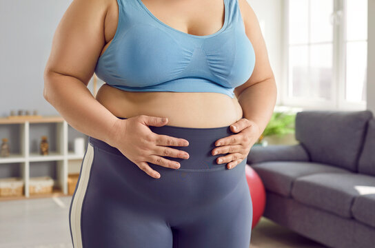 Cropped shot white woman in lingerie holding fat belly. Large