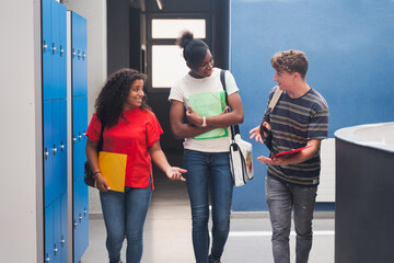 Three student friends going back to classes arriving to College, walking in school