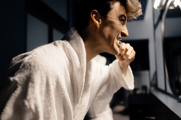 Young man brushing teeth in hotel bathroom
