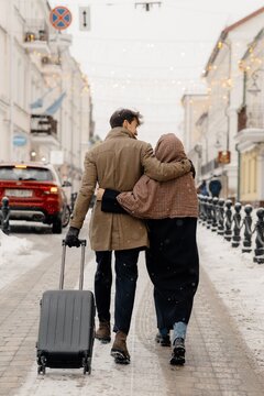 Couple with suitcase walking on street and hugging
