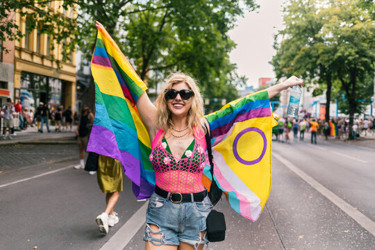 Woman with Progress and Pride flag marching on the street