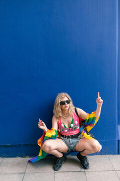 Energetic Woman at Pride Sitting by Blue Wall