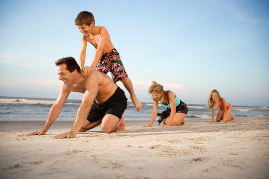 Family at the beach playing leap frog. Horizontal shot.
