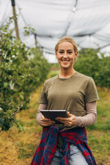 Fototapeta premium Portrait of a pretty blond woman in the orchard.