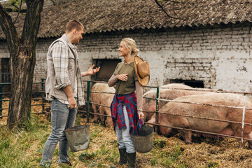 Two villagers working on their farm and feeding the pigs.