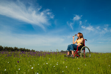 Happy handicapped woman on a wheelchair over a green meadow