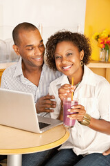 Two people at a cafe drinking frozen beverages and using a laptop. Vertical shot.