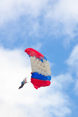 Man with three-colored parachute against cloudy sky