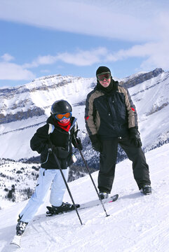 Family downhill skiing vacation - father and daughter in scenic winter Rocky mountains